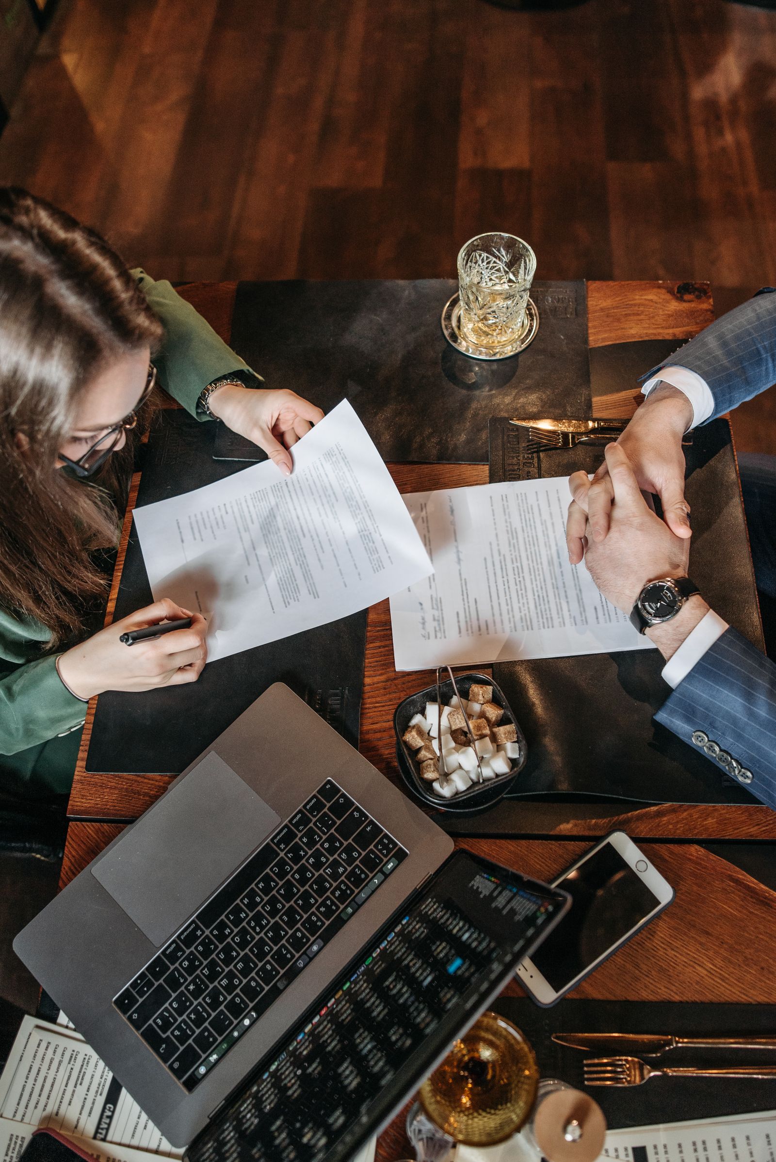 Two people signing a business contract beside a laptop