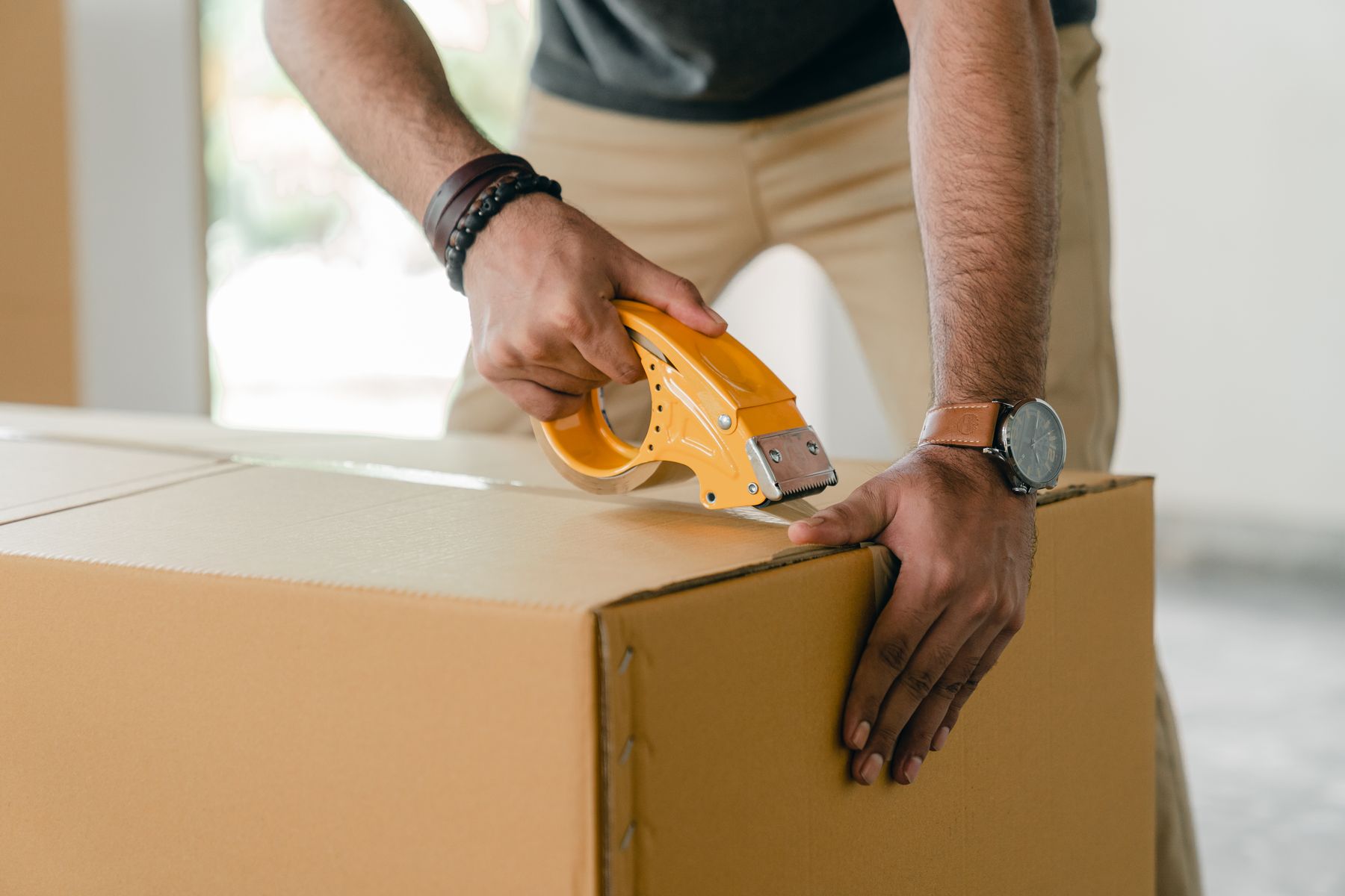 Hands sealing a carton on a warehouse floor