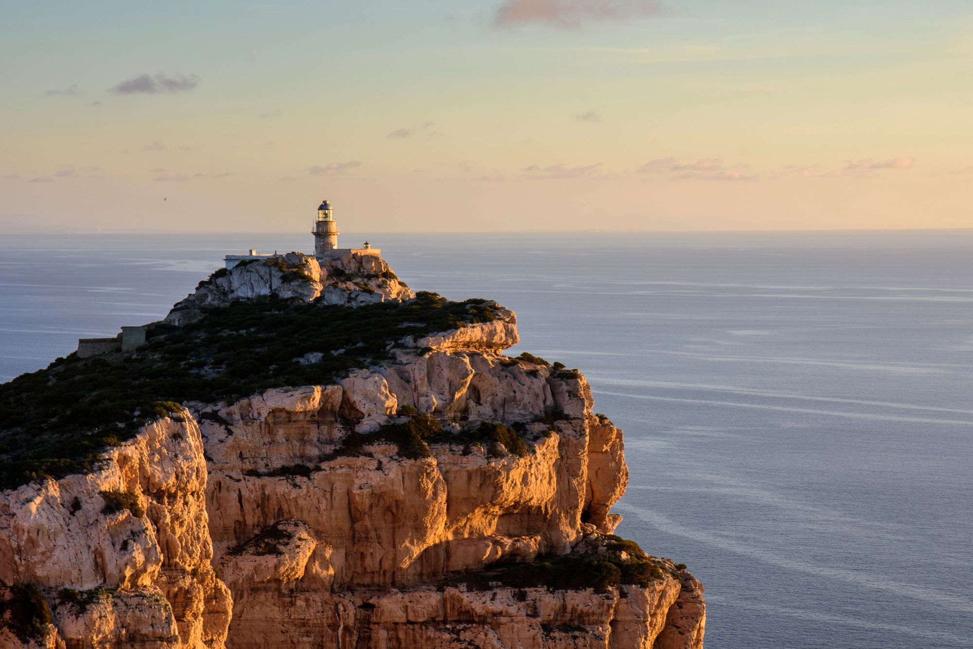 Lighthouse on a cliff above the water at dusk