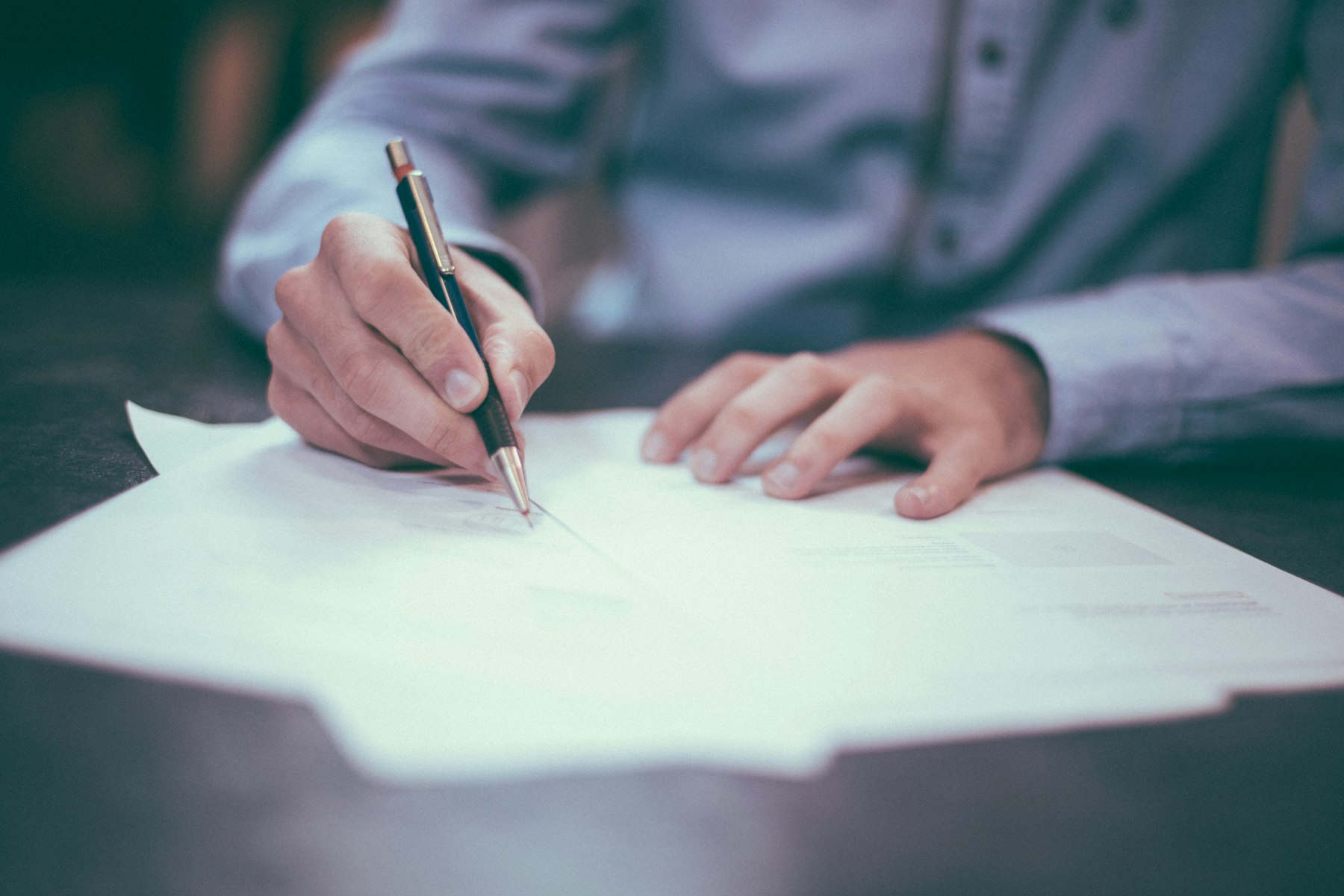 Hands signing a document on a desk