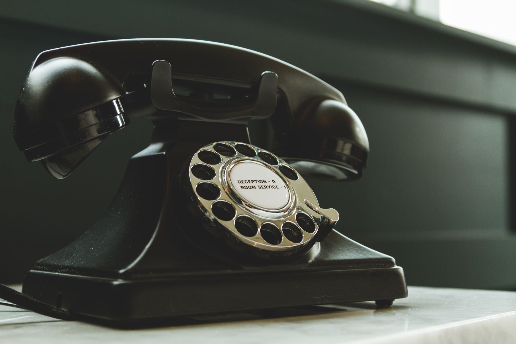 Black rotary telephone on a stone desk