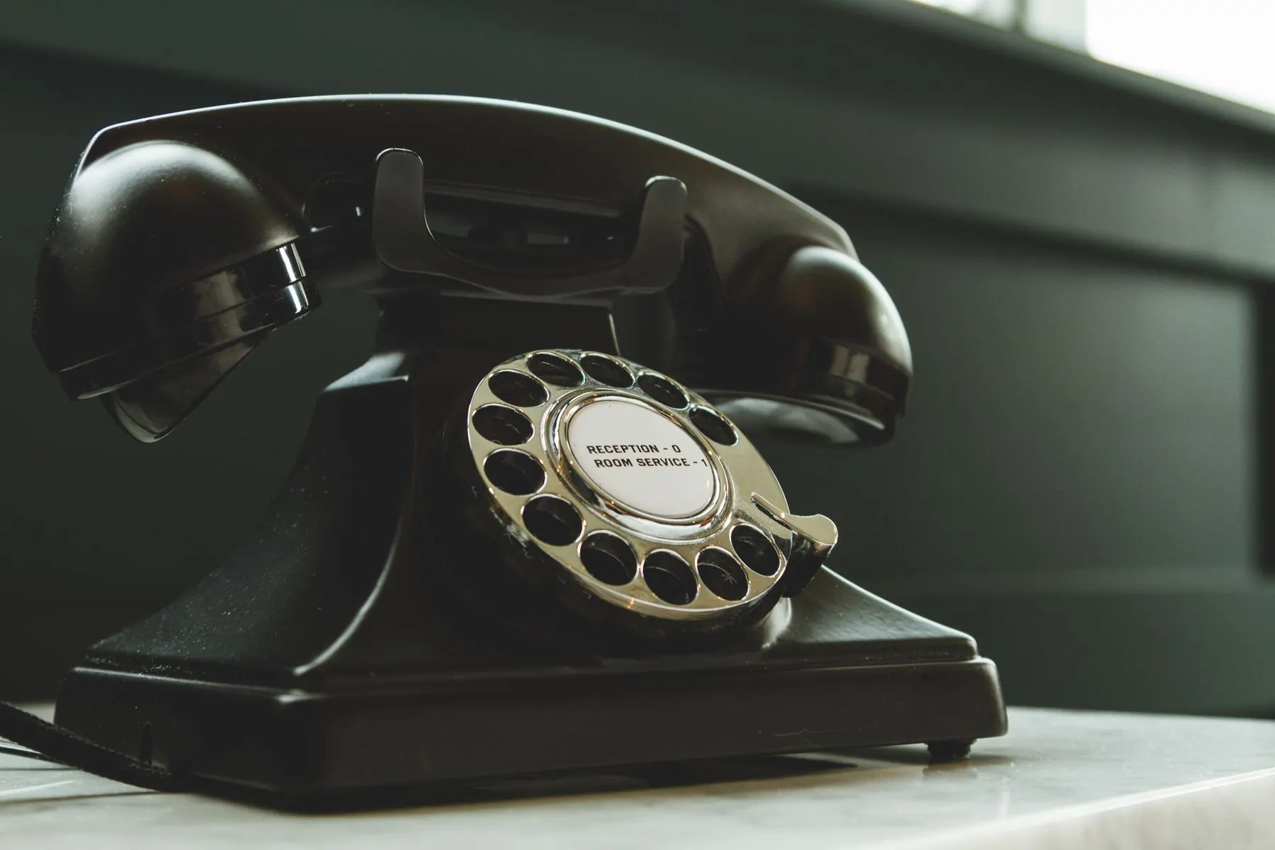 Black rotary telephone on a stone desk