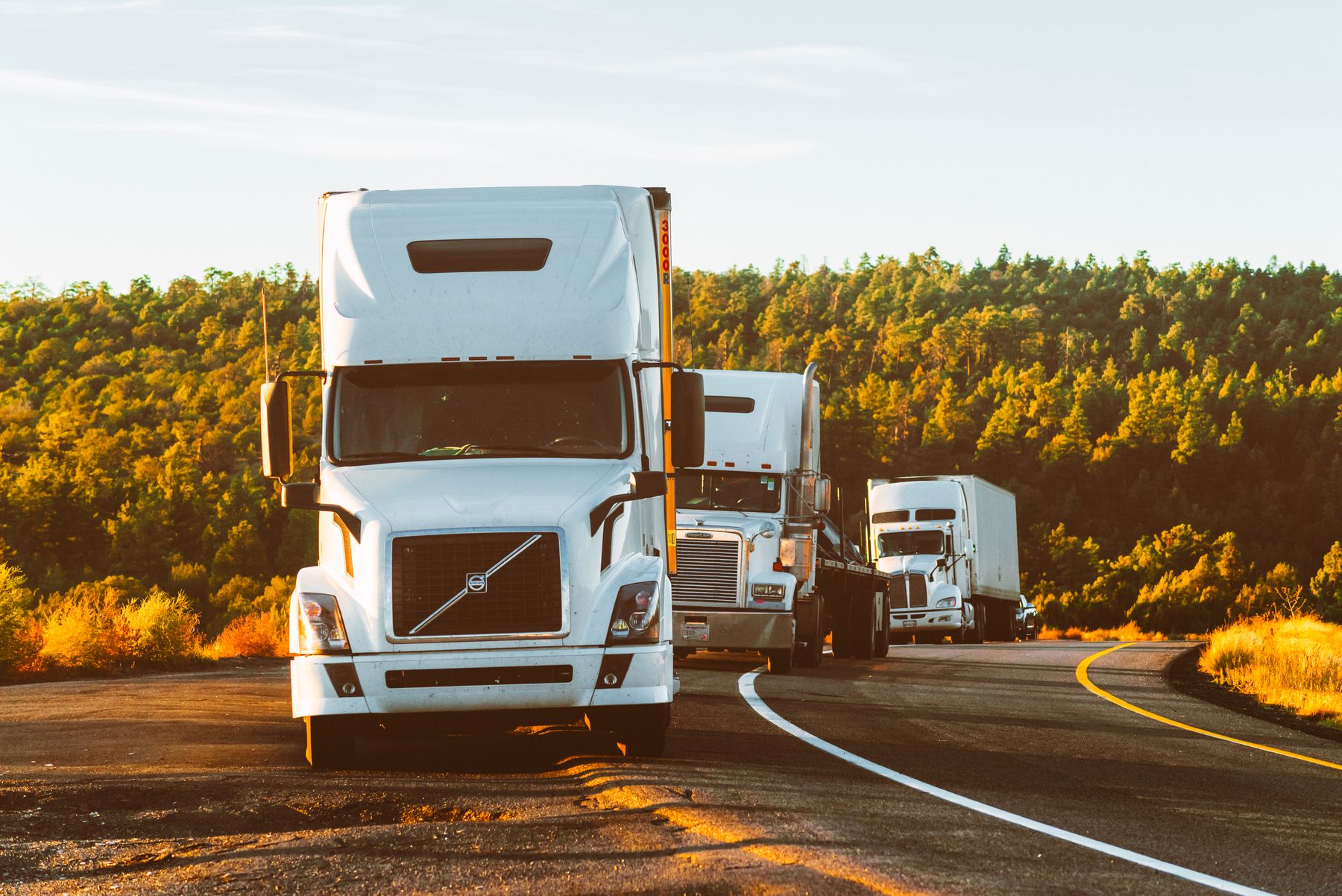 Unmarked semi-trucks on a highway at golden hour