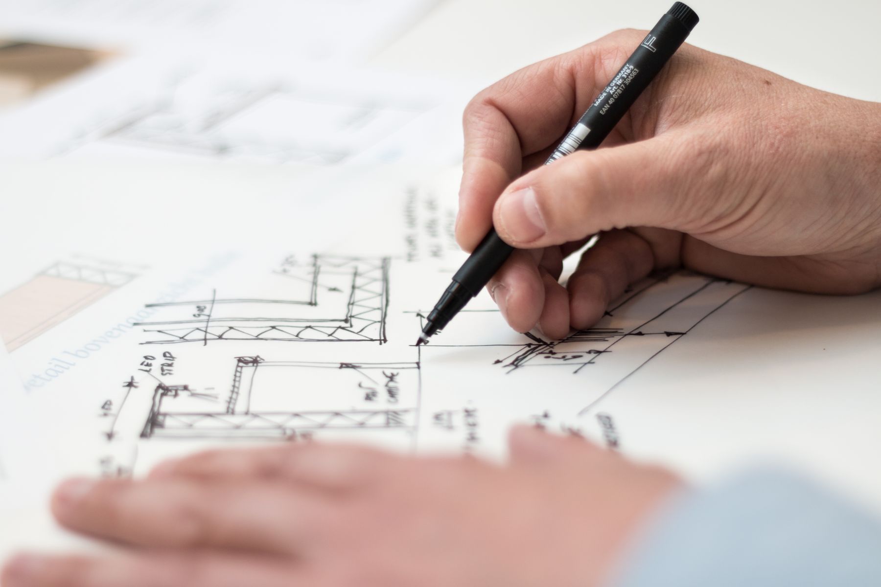 Hands drawing a technical plan on paper